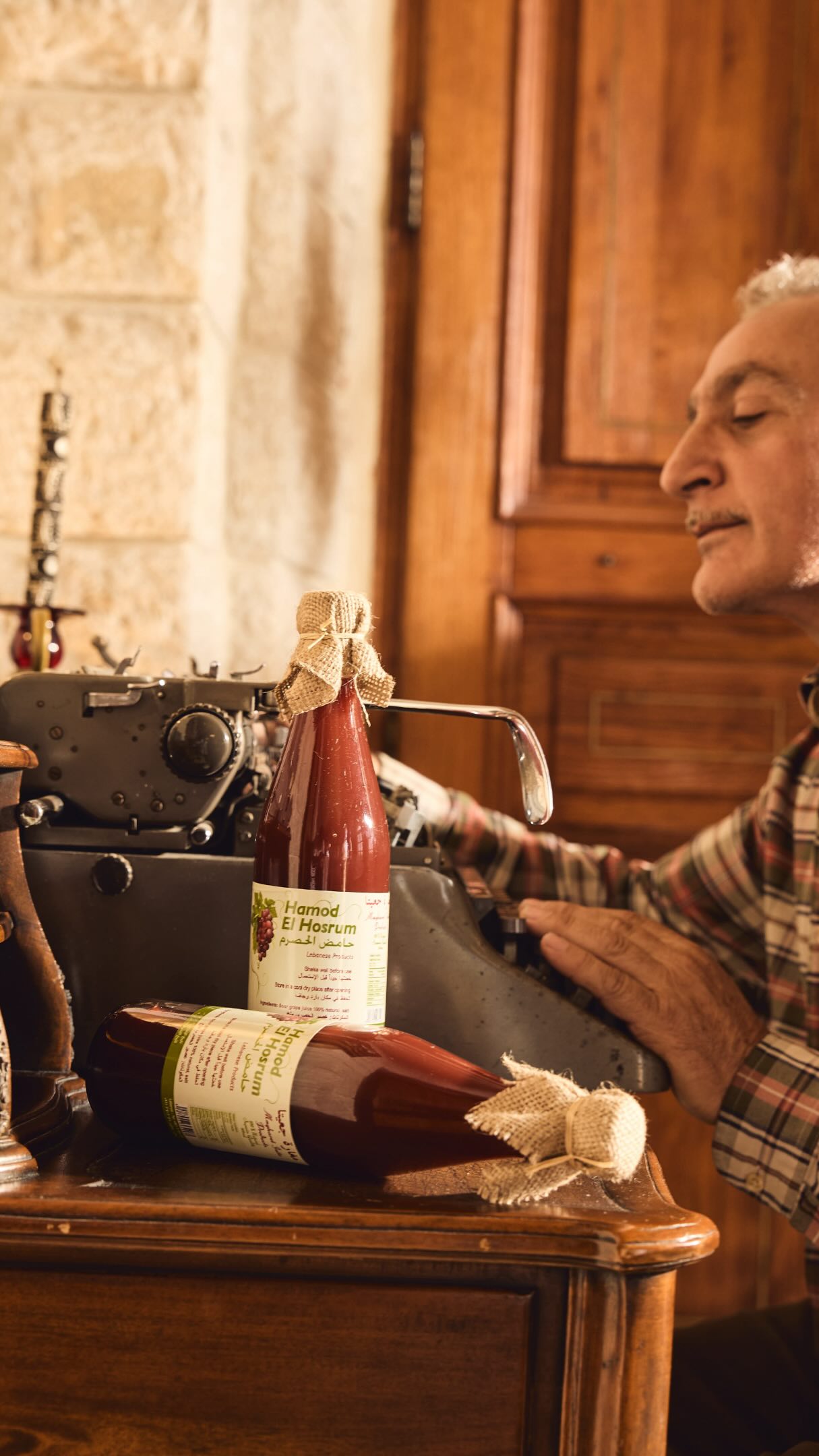 The Artisan typing at vintage typewriter with bottles of Hamod El Hosrum